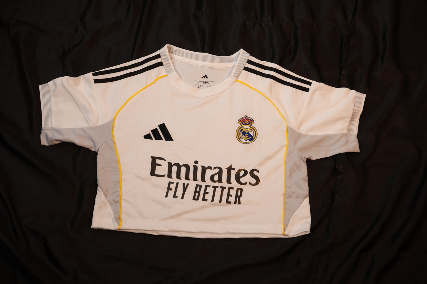 White sports jersey with black stripes and branding on a dark background