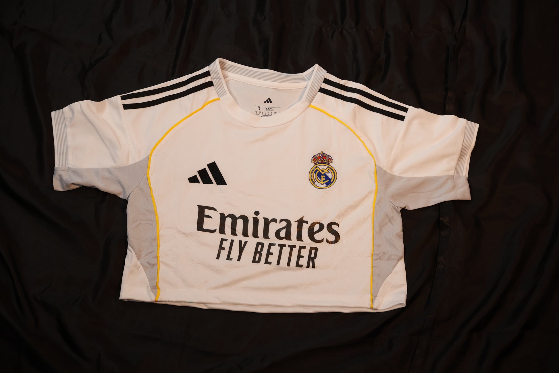 White sports jersey with black stripes and branding on a dark background